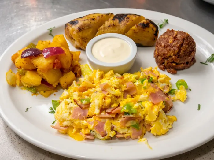 Desayuno tradicional con huevos revueltos, papas, frijoles y plátano