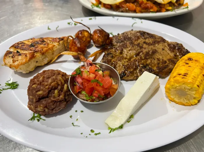 Plato de pollo y carne a la parrilla con elote y frijoles