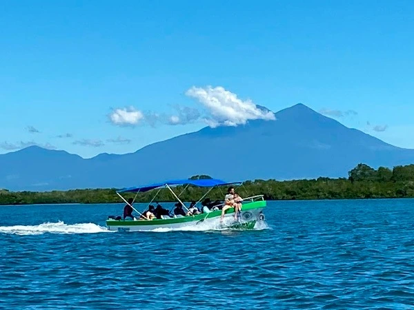 Lancha navegando con pasajeros y vista al volcán de San Vicente