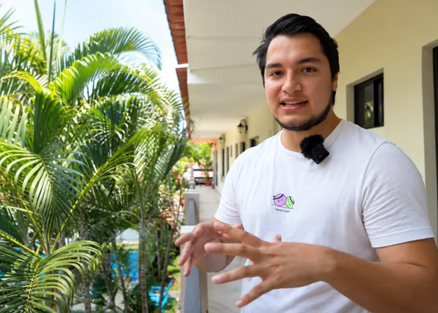 Vlogger frente a una habitación del hotel entre palmeras